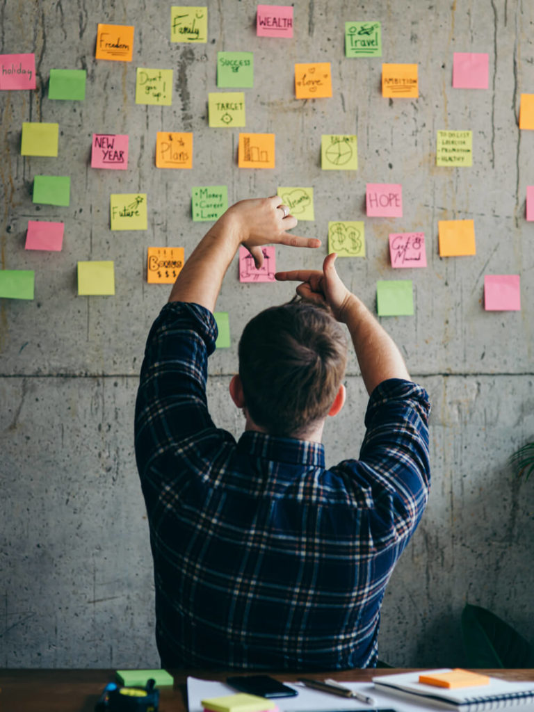 An internet entrpreneur focusing on his wall of post-it notes